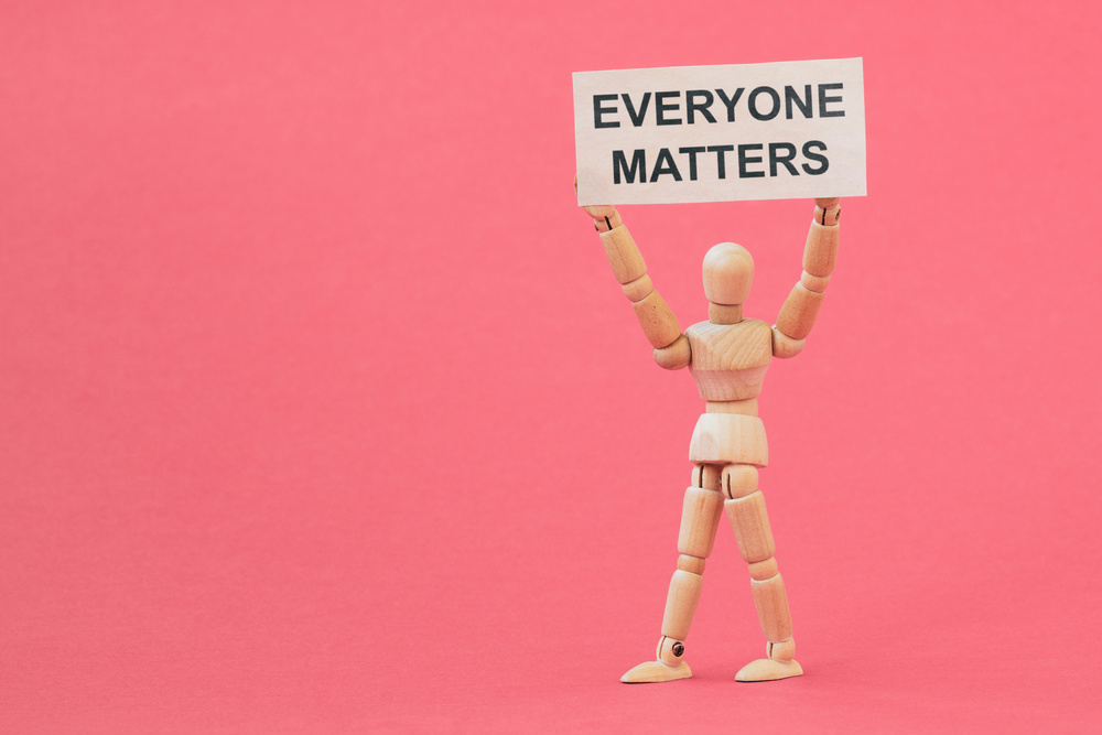 Figurine Holding an Everyone Matters Placard